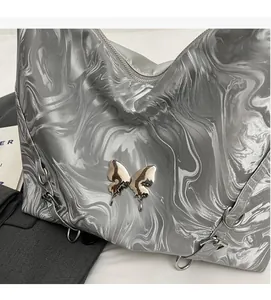 Detail of silver liquid metal marble texture and butterfly hardware on the fashion bag