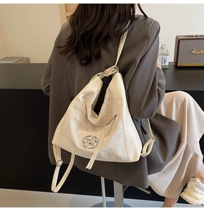 Dettaglio borsa hobo color crema con trama a pieghe e logo in metallo argentato
