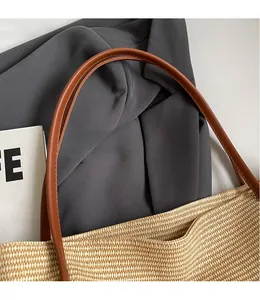 Close-up of woven straw tote bag with smooth dark brown shoulder strap detail