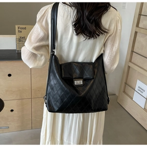 Detailed view of a black quilted shoulder bag with silver turn-lock and chain strap