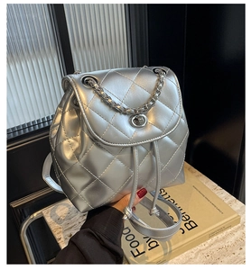 Close-up of silver quilted backpack with metallic chain and drawstring closure