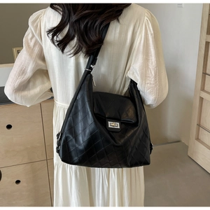 Detail of black quilted leather hobo bag with silver twist lock and wide shoulder strap