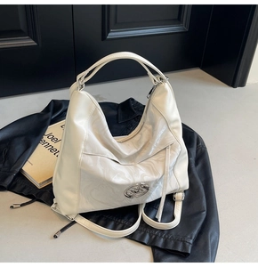 Dettaglio della borsa hobo crema con pannello effetto marmo e logo circolare in metallo