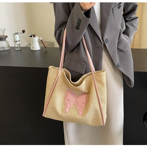 Detail of straw woven tote bag with pink butterfly patch worn on a grey blazer