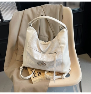 Dettaglio borsa hobo bianco panna con inserto in marmo e logo metallico intrecciato