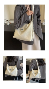 Detailed close-up of cream quilted tote bag showing metal twist lock and texture