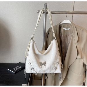 Detail of white marble print tote bag with silver butterfly emblem and metal chain straps