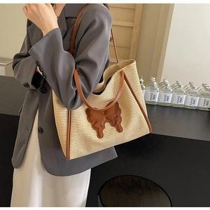 Close-up of woven straw tote bag with brown leather butterfly patch and shoulder straps