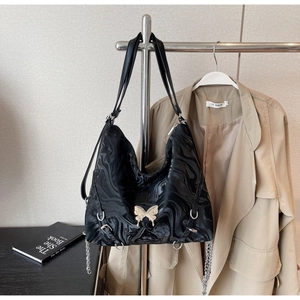 Detail of black tote bag featuring marble texture and golden butterfly metal ornament