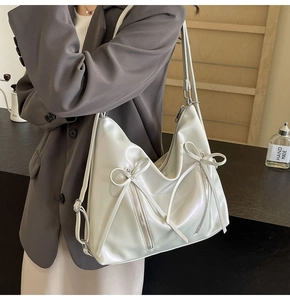 Détail du sac à dos beige nacré avec nœuds, zips argentés et texture au fini satiné