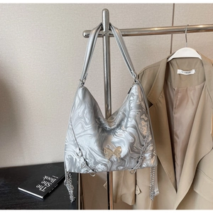 Detail of silver tote bag with marble texture, golden butterfly buckle and chain strap