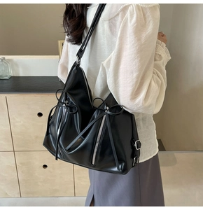 Détail du sac bandoulière noir en similicuir avec ruban et fermetures éclair argentées