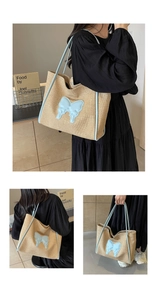 Detail of straw woven tote bag with blue leather trim and 3D butterfly patch accessory