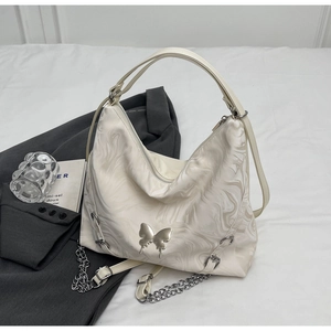 Detailed shot of white marble texture handbag with silver butterfly ornament and metal chain