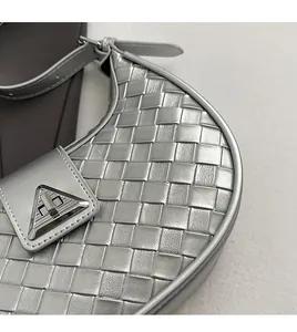Detail of silver metallic woven handbag with triangle buckle and intricate texture