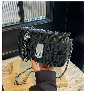 Detail of black quilted leather shoulder bag with silver chain and ball ornament