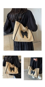 Detail of woven straw tote bag with a large black leather bow and long shoulder straps