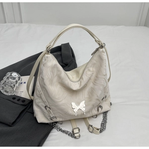 Detail of off-white marble pattern tote bag with silver butterfly and chain strap decor