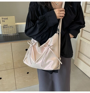 Détail du sac hobo rose nacré avec décoration de nœud et texture en similicuir doux