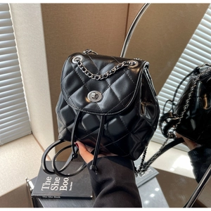 Detail of black quilted leather mini backpack with silver twist lock and chain strap