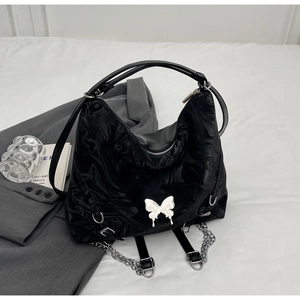 Detail of black hobo bag with marble texture, white butterfly buckle and silver chains