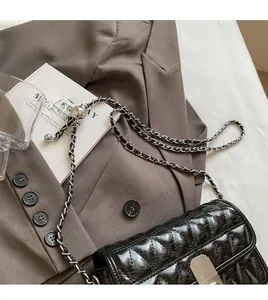 Detail of black quilted leather shoulder bag featuring silver chain and adjustable metal ball