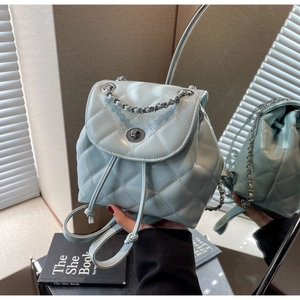 Close-up of light blue quilted mini backpack with glossy finish and metal chain handle