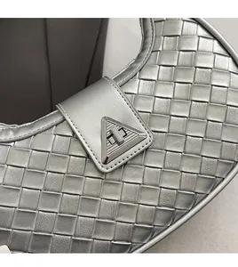 Close-up of woven silver crescent bag showing the metallic triangular metal lock detail