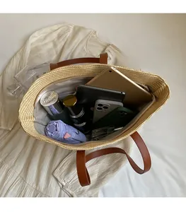 Detail showing spacious interior of woven straw tote bag with brown leather handles