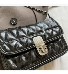 Close-up of black quilted bag with silver twist lock and shiny oil wax leather texture