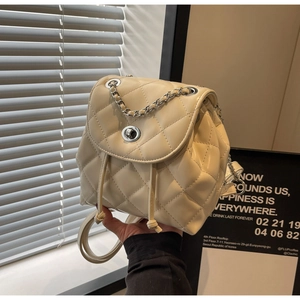 Close-up of cream quilted PU leather backpack with silver twist lock and chain detail