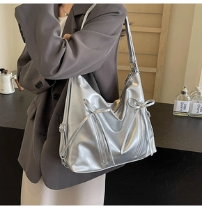 Détail du sac à bandoulière argenté métallisé avec nœuds porté par un mannequin