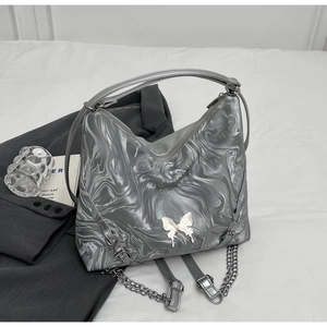 Close-up of marble pattern tote bag featuring silver metal butterfly and chain strap