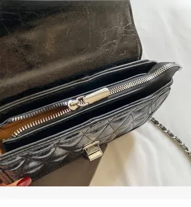 Detailed macro view of smooth metal zipper and inner lining of black quilted chain bag