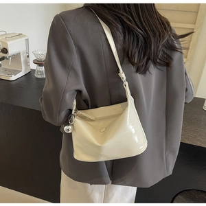 Detail of cream crocodile embossed handbag with silver ball pendant and sleek strap