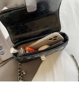 Macro view of black quilted chain bag interior showing storage space for phone and makeup