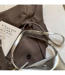 Detail showing the adjustable long strap and smooth metallic silver surface of the bag