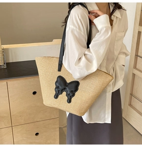 Detail of summer straw tote bag with black leather butterfly patch and long shoulder strap