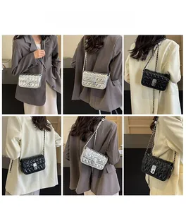 Close-up of quilted chain square bag with metallic rotating lock and strap detail