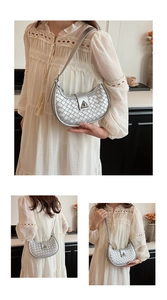 Detail of silver woven crescent bag showing the metallic triangular buckle and texture