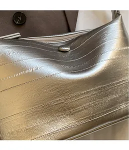 Detail of silver crossbody bag with horizontal embossed texture and metal magnetic clasp