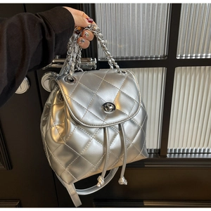 Close-up of silver quilted backpack with metallic chain and twist lock detail