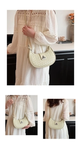 Detail of cream woven shoulder bag featuring a half-moon shape and silver triangular clasp
