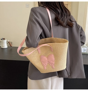 Detail of straw tote bag with pink bow and PU straps worn by a model in casual setting