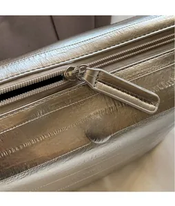 Macro shot of smooth champagne gold hardware zipper on minimalist square shoulder bag