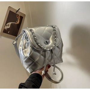 Detail of silver metallic quilted backpack featuring diamond stitching and chain strap