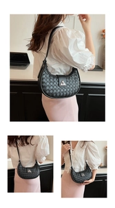 Detail of black woven crescent bag with silver triangle buckle and adjustable strap