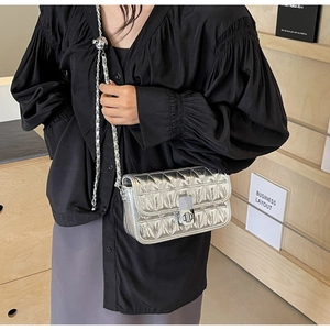 Detail of silver quilted chain bag featuring metallic finish and rotating metal lock