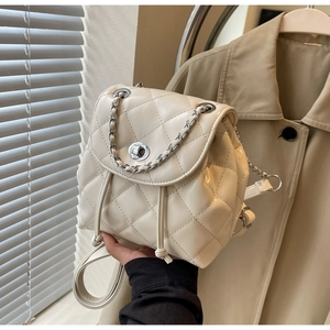 Detail shot of the cream white quilted faux leather backpack with silver chain and twist lock