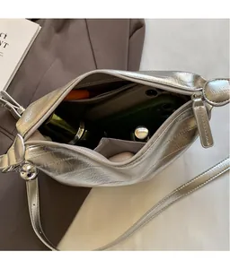 Close-up of silver crossbody bag interior showing spacious storage for phone and cosmetics